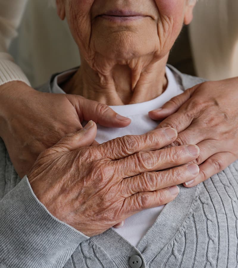Elderly woman with hands over her heart