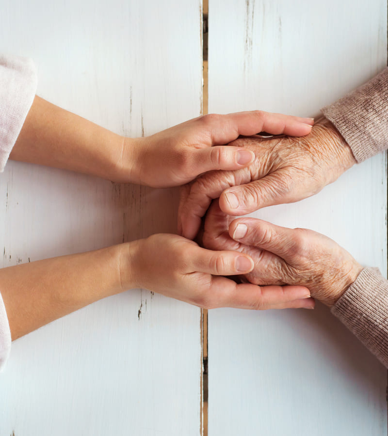 Young hands holding older person's hands.