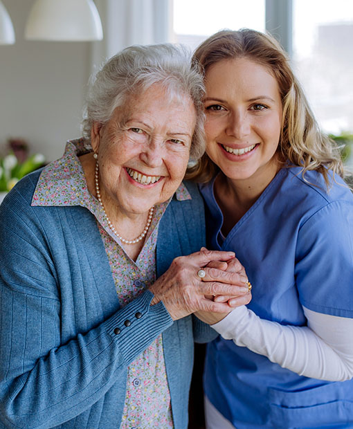 Elderly woman and young nurse holding hands and smiling